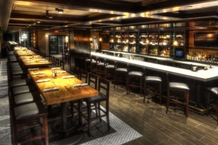 Modern upscale bar and dining area with wooden tables and stylish lighting for entrepreneurs and professionals.