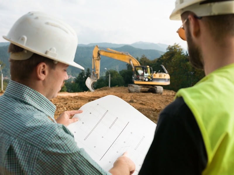A trades professional reviewing project plans on a local job site