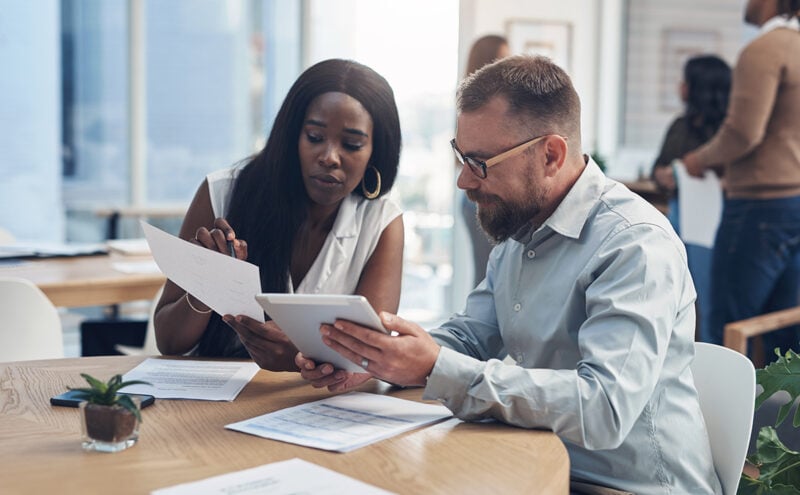 Two North Carolina business partners reviewing financial paperwork together, using the entrepreneurship skills needed to grow a company.